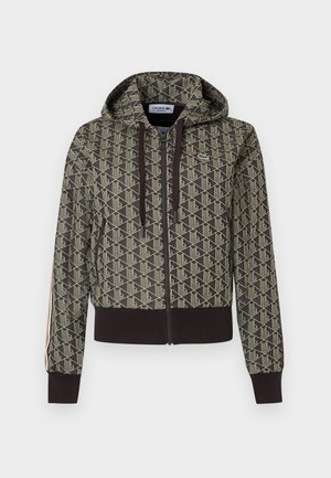Jachetă cu glugă și fermoar, cu model geometric bej și verde închis, manșete și tiv reiate, dungi laterale și logo Lacoste pe piept.