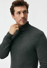 Szary sweter z golfem wykonany z miękkiego materiału, z wysokim kołnierzem, prążkowanymi mankietami i dopasowanym krojem tworzącym smukłą sylwetkę.