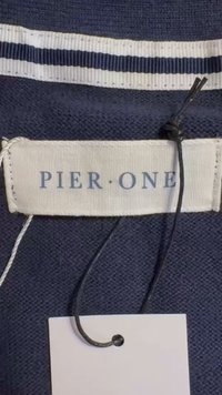 Marineblåt stof med en vævet tekstur har et mærke med påskriften "PIER ONE" i lyseblåt. Et hvidt mærke er fastgjort med en sort snor.
