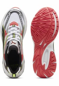 Sportschuhe mit einem weißen Mesh-Obermaterial, schwarzen und roten Akzenten sowie fluoreszierenden grünen Details. Verfügt über eine strukturierte rote Gummisohle.