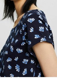 Granatowa bluzka z krótkim rękawem w biało-niebieski kwiatowy wzór. Miękka tkanina i okrągły dekolt, z podwiniętymi mankietami.