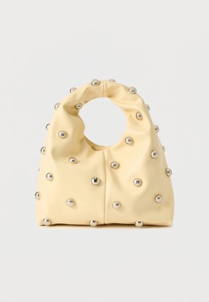Gele zachte handtas met ronde zilveren studs die het oppervlak bedekken en een cirkelvormige handgreep boven in het midden.