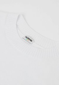 Weißer Strickpullover mit geripptem Rundhalsausschnitt. Sichtbares Etikett mit der Aufschrift "TEZENIS KIDS." Glatte Textur ohne Muster oder Akzente.