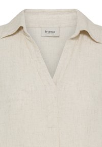 Chemise en lin beige avec col ouvert et encolure en V, avec une étiquette de marque "fransa" cousue à l'intérieur du col.