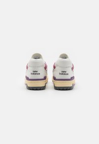 Fehér és lila sportcipők, texturált bőrből készült felsőrész, párnázott középtalp és kontrasztos fekete gumitalp "new balance" brandinggel.
