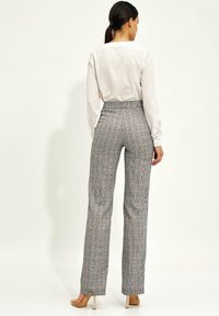 Spodnie w szaro-pomarańczową kratę z wysokim stanem i dopasowanym krojem, z prostymi nogawkami i delikatną teksturą na całej powierzchni.