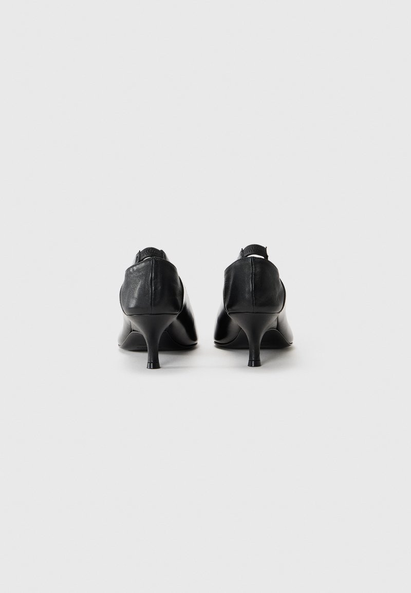 Schwarze Leder-Pumps mit hohen Absätzen, die über einen konischen Absatz und eine glatte Textur verfügen. Sie sind mit einer eleganten Silhouette und minimalen Details gestaltet.