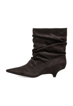 Bota de tobillo de ante negro con caña caída, puntera puntiaguda y tacón bajo tipo kitten, vista lateral sobre fondo blanco.