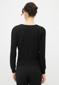 Maglione nero lavorato a maglia con maniche lunghe, scollatura a barchetta e un design aderente con una leggera lucentezza. Dettagli a costine sui polsini e sull'orlo.