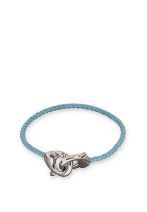 Pulsera de cuero trenzado de color azul claro con un gran cierre de nudo entrelazado de plata, centrado sobre un fondo blanco.