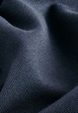 Tume tumesinine, tekstuuriga kangas peente ribadega ja siledapinnaline, millel on voldid ja kõverused, rõhutades selle pehmust ja paindlikkust.