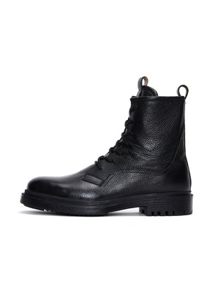Botas de cuero negro con cordones, acabado texturizado, suela plana, punta redondeada y bucle para tirar. Incluyen un collar acolchado y suela robusta.