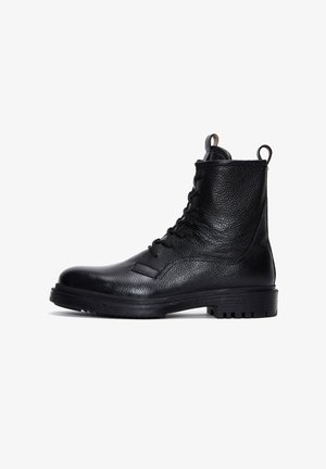 Schwarze Leder-Schnürstiefel mit strukturiertem Finish, flacher Sohle, runder Spitze und Zuglasche. Verfügt über einen gepolsterten Kragen und ein robustes Profil.