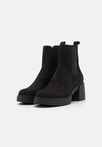 Botines de ante negros con un tacón ancho, paneles laterales elásticos y una lengüeta, que presentan una textura suave y un diseño de punta redonda.