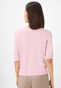 Lys rosa strikket sweater med korte ærmer, subtil ribbet kant og halsudskæring, der har en glat tekstur og en afslappet pasform.