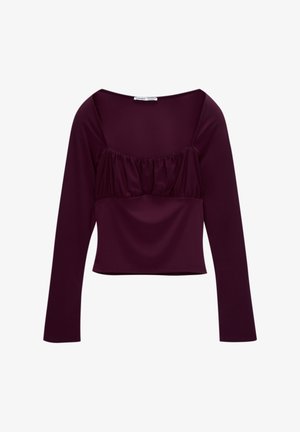 Haut bordeaux à manches longues avec un décolleté carré et des détails froncés au niveau de la poitrine. Tissu lisse, longueur cropped et design ajusté.