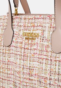 Borsa in tweed con fili rosa, bianchi e dorati, dotata di manici in pelle beige e placca con logo dorato "GUESS EST 1981".
