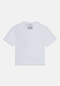 Balta medvilninė marškinėliai trumpomis rankovėmis, su apvaliu iškirpimu ir juodu logotipu "EA7 Emporio Armani", atspausdintu viršutiniame nugaros segmente.