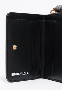 Wnętrze czarnego skórzanego portfela z wieloma miejscami na karty, szczegóły wykończenia w kolorze złotym oraz białym napisem "BIMBA Y LOLA." Gładka tekstura.