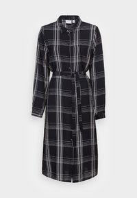 Vestido de xadrez preto e branco com frente com botões, mangas compridas e um cinto combinando na cintura. Feito de um tecido leve.