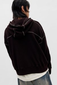 Donkerbruine hoodie met een gewatteerd patroon, contrasterende stiksels en een ontspannen pasvorm. Voorzien van een capuchon en geribde manchetten.