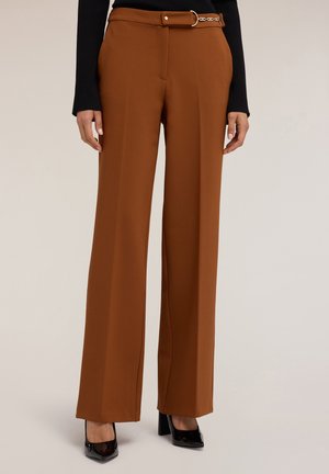 Pantalones de pierna ancha marrones, confeccionados con una tela suave, que cuentan con una cintura con cinturón y hebilla dorada, y pliegues marcados, combinados con zapatos negros de tacón.
