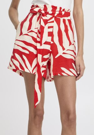 Red and cream shorts featuring a leaf pattern, a tied belt at the waist, and a relaxed fit. Made from lightweight fabric with pockets.