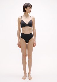 Bralette noire sans coutures et culotte de bikini taille haute. Tissu lisse, design minimaliste, sans ornement, avec bretelles réglables sur le bralette.