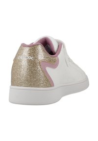 Zapatilla blanca con una superficie texturizada, acentos en rosa y un tacón dorado brillante. Presenta una punta redondeada y un diseño de cordones.
