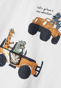 Pomarańczowy Jeep z dużymi czarnymi oponami przejeżdża przez białe tło, a na miejscach kierowcy siedzą żyrafa i dinozaur, powyżej kolorowy tekst graficzny.