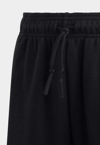 Pantaloni sportivi neri con vita elastica e cordino regolabile. La trama del tessuto è liscia con una finitura opaca.