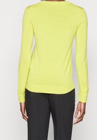 Bright yellow sweater with long sleeves, a ribbed neckline, and cuffs. Made from soft material, featuring a fitted design and plain texture.