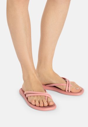 Rosa Flip-Flops mit einer weichen Gummisohle und zwei überkreuzten Riemen, die für Komfort und lässigen Tragekomfort entworfen wurden.