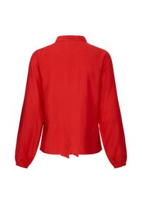 Chemisier rouge à manches longues avec col, poignets élastiques et un ourlet légèrement raccourci, vu de dos sur fond blanc.