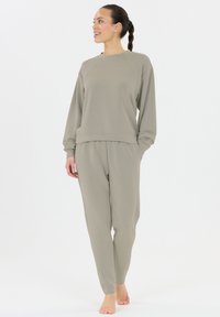 Ljust grått lounge-set bestående av en långärmad tröja med raglanärmar och matchande tapered byxor. Mjukt tyg och avslappnad passform.