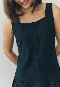 Rochie din in de culoare albastru închis, cu decolteu pătrat, închidere cu butoane pe față și tiv plisat. Textură netedă, design fără sleeves.