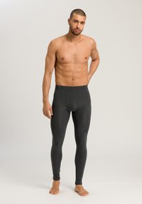 Leggings noirs ajustés en tissu extensible, avec une texture lisse et une taille sans couture, portés par un mannequin pieds nus.