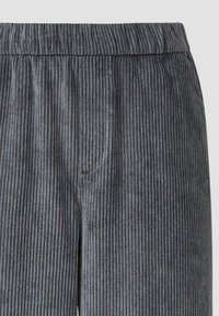 Graue Cordhosen mit vertikaler Rippstruktur, elastischem Bund und seitlichen Taschen. Der Stoff hat ein weiches, samtiges Aussehen.