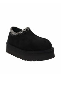Zapato negro de ante sin cordones con una suela de plataforma texturizada y costuras blancas en contraste a lo largo del cuello. Diseño de punta redondeada.