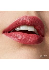 Dyp ruby leppestift på glatte, fyldige lepper med naturlig glans. Synlige teksturdetailler og hvite tenner som titter frem.