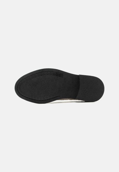 Semelle de chaussure noire avec une surface lisse et texturée et un contour de coutures visible autour des zones des orteils et du talon.