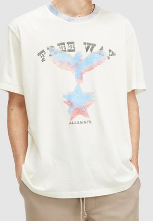 Osoba nosząca kremową koszulkę z wyblakłym czerwonym i niebieskim nadrukiem gwiazdy i ptaka oraz tekstem "FREE WAY" i "ALLSAINTS" z przodu.
