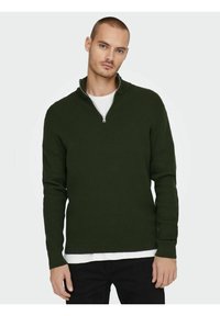 Dark green, ribbed zip-neck sweater, made of textured fabric. Features long sleeves and a layered look with a white undershirt.