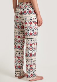 Creme-pantalon met bloemmotief, voorzien van rode en groene accenten. Gemaakt van zachte stof, met een elastische tailleband en wijde pijpen.
