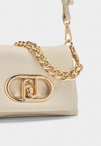 Borsa a mano in pelle beige con tracolla a catena in tonalità oro e chiusura con logo. La superficie texturizzata e la forma strutturata aggiungono eleganza.