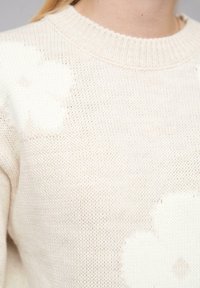 Cremfarbener Strickpullover mit großen, weichen Blumenmustern, rundem Ausschnitt und strukturiertem, offenem Gewebedesign.