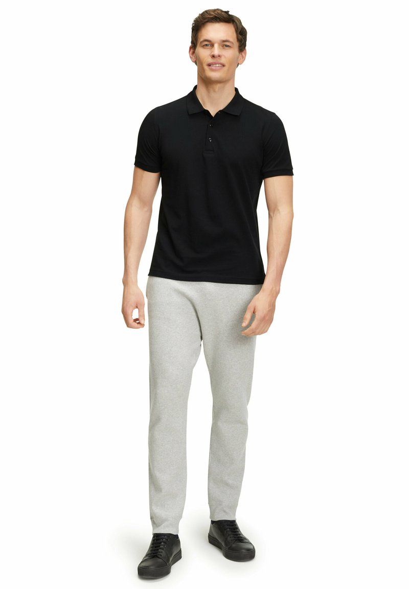 Czarna koszulka polo z klasycznym kołnierzykiem, w połączeniu z jasnoszarymi spodniami dresowymi i czarnymi sneakersami. Prosty design, dopasowana sylwetka, minimalne detale.