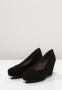 Black suede wedge shoes with a rounded toe and a smooth texture, featuring a platform sole and a slight heel for added height.