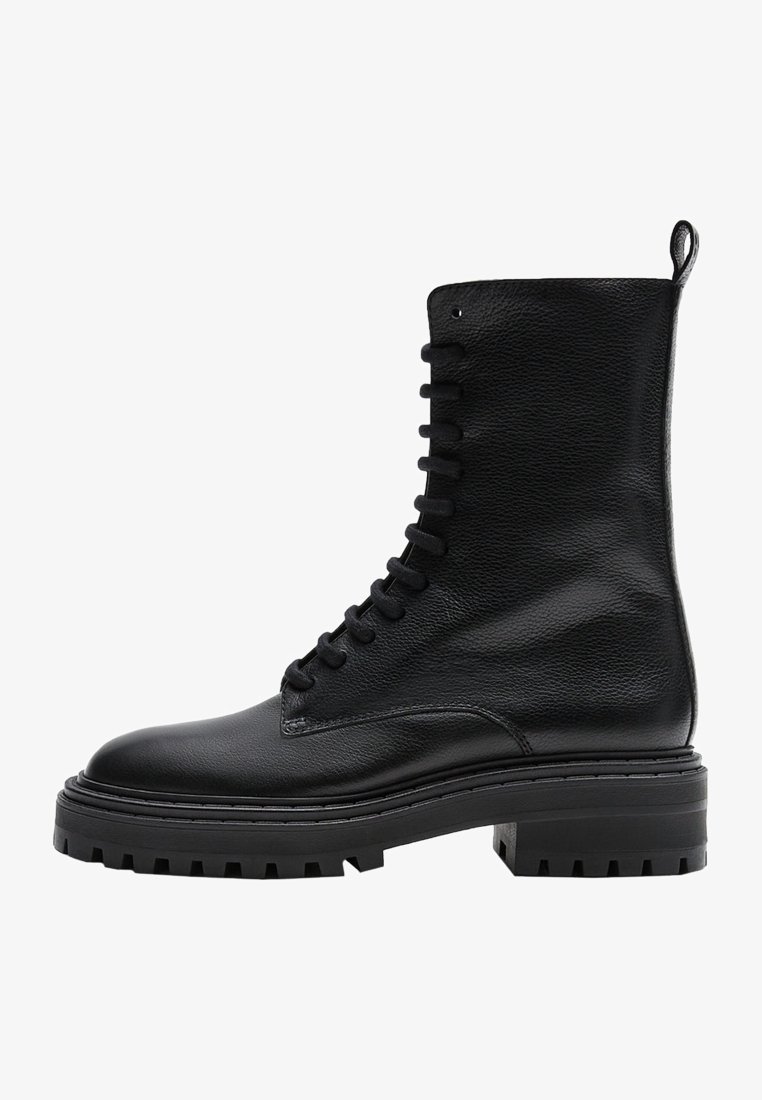 Botte de combat en cuir noir à lacets avec semelle épaisse à crampons et languette à l'arrière, vue du côté extérieur.