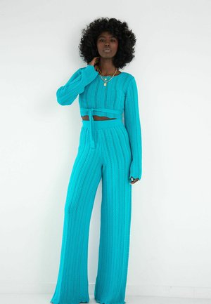Turkusowy dzianinowy zestaw składający się z krótkiego, ribbowanego topu z wiązaniem oraz szerokich spodni o wysokim stanie z teksturowanym wzorem.